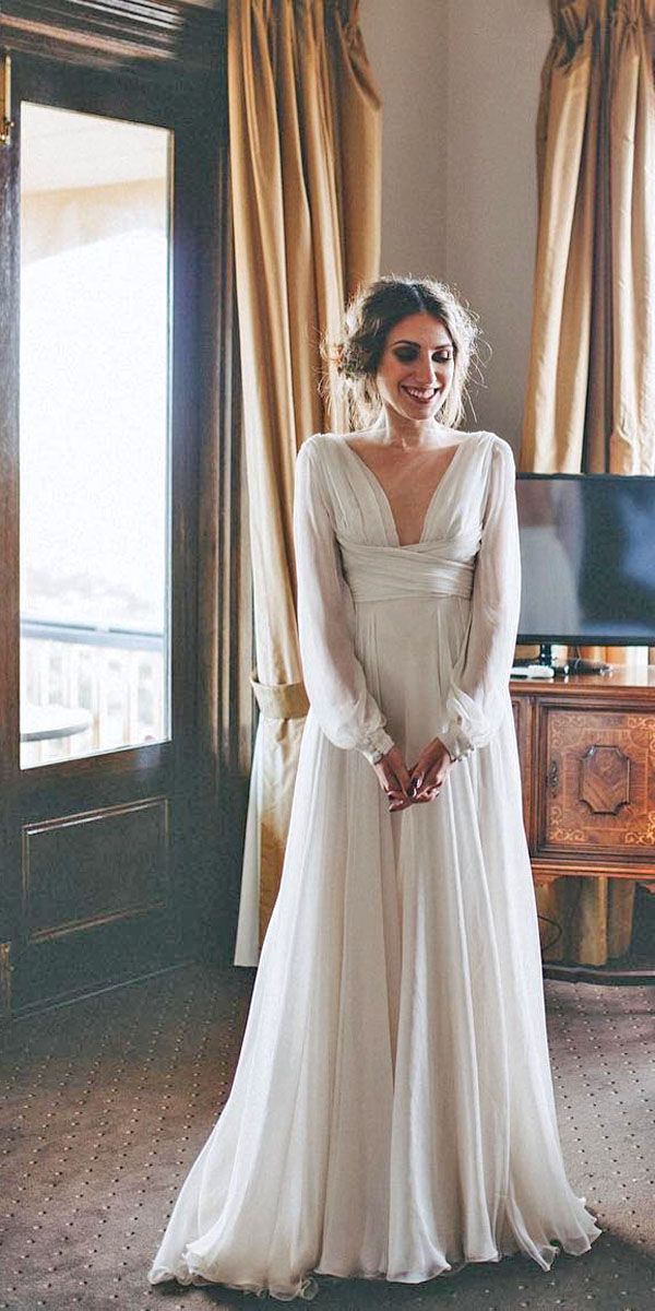 a woman standing in front of a window wearing a wedding dress