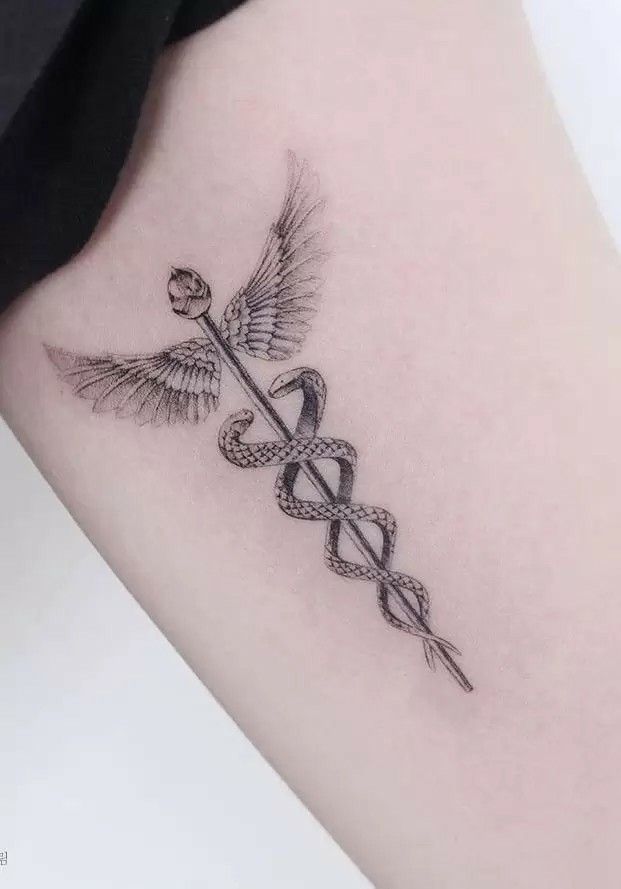 a black and white photo of a tattoo with an arrow on the side of a woman's leg