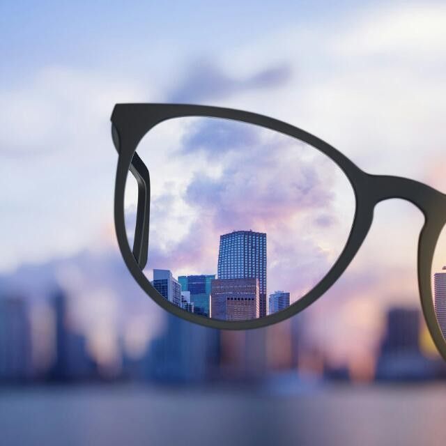 a pair of glasses sitting on top of a wooden table in front of a cityscape