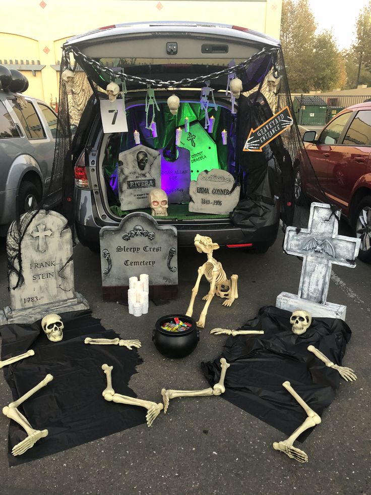 halloween decorations are arranged in the trunk of a car, including skeletons and tombstones