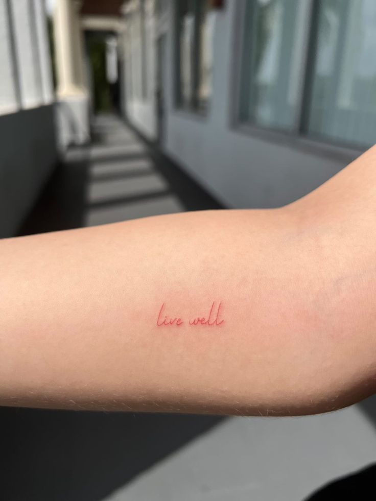 a woman's arm with the word love written in red ink on her left arm