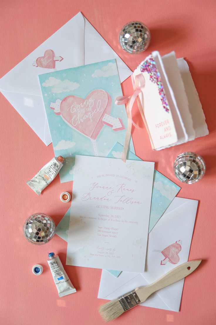 the wedding stationery is laid out on top of the pink tablecloth and paper