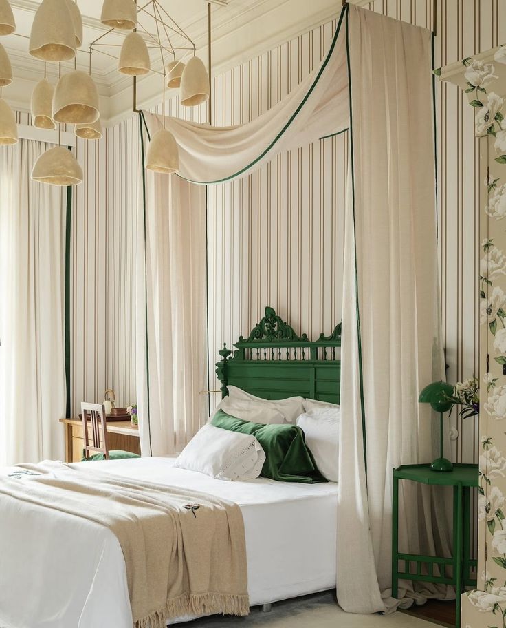 a bed with white sheets and green headboard in a room that has curtains on the walls