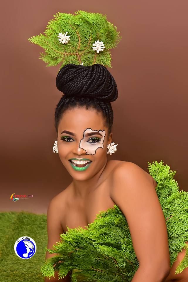 a woman with painted face and green leaves on her head is posing for the camera