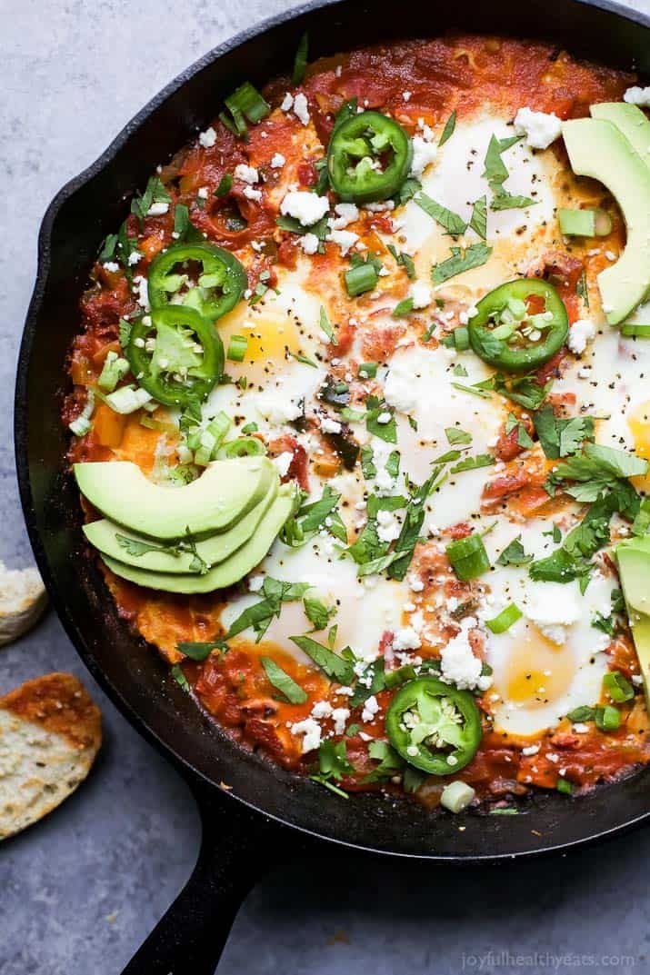 an iron skillet filled with eggs, cheese and green peppers next to crackers