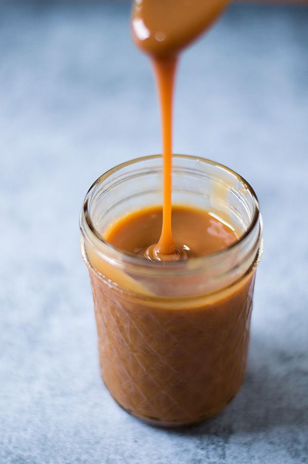 a jar filled with caramel sauce being drizzled on top of it