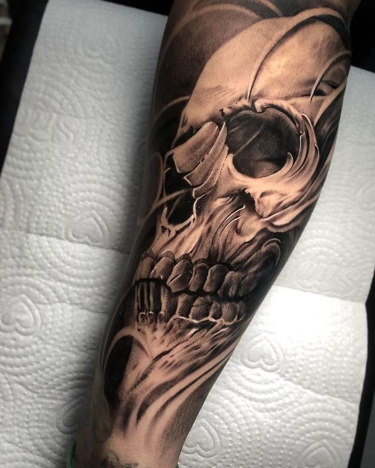 a man's arm with a skull and helmet tattoo on the left side of his leg