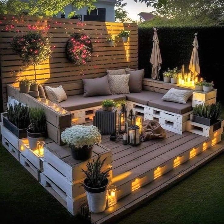 an outdoor seating area is lit up with candles and potted plants on the deck