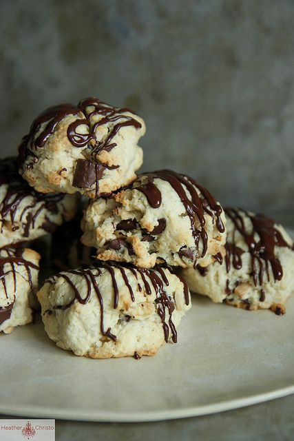 cookies with chocolate drizzled on them sitting on a white plate in front of a gray background