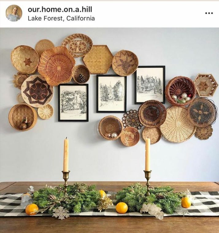 a wooden table topped with plates and candles next to pictures on the wall above it