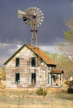 an old wooden house with a windmill on top