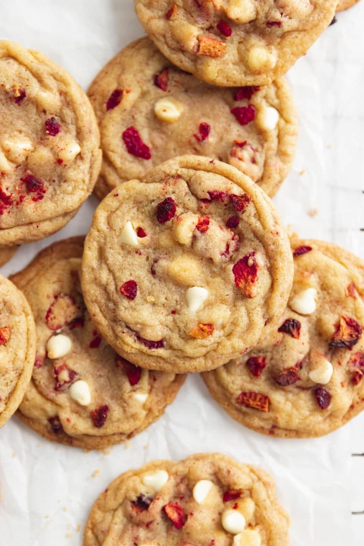 a pile of cookies with white chocolate chips and cranberry toppings on top