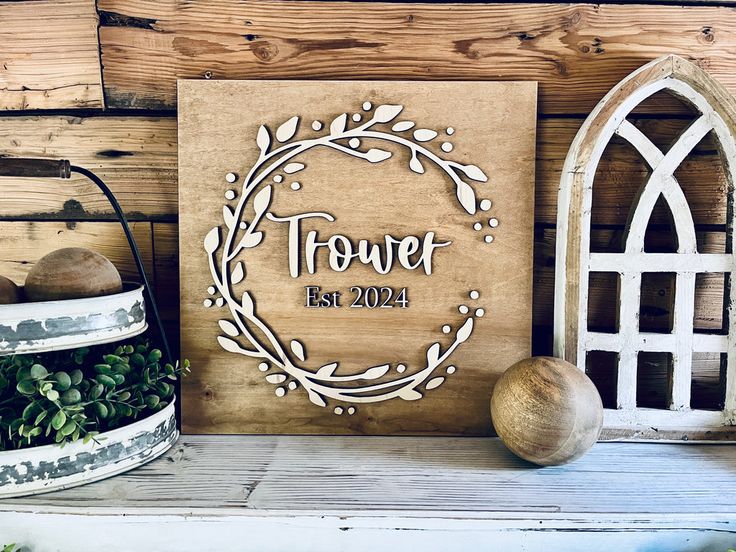 a wooden sign sitting on top of a shelf next to a potted plant and vase