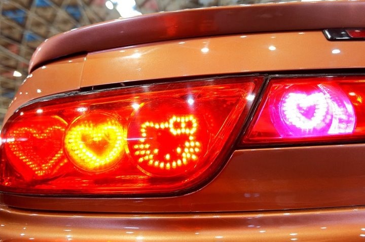 the tail lights of an orange car with hearts on it's rear bumpers