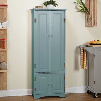 a tall blue cabinet sitting in the corner of a room next to a table and shelves