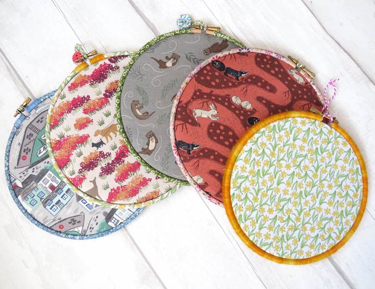 four round placemats with different designs on them sitting next to each other in front of a white wooden surface