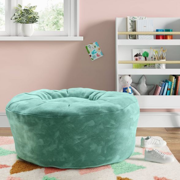 a large green bean bag chair sitting on top of a rug next to a window