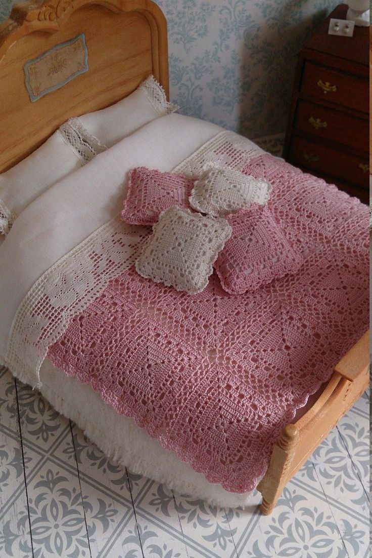 a bed with a pink blanket on top of it next to a night stand and dresser