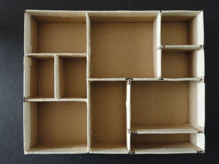 an open cardboard box with multiple compartments on the top and bottom, sitting on a black surface