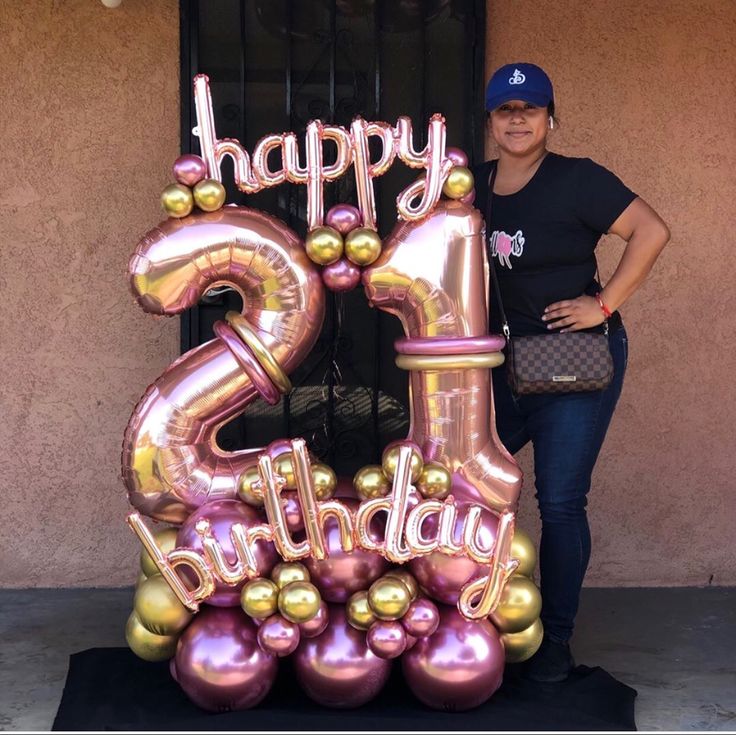 a woman standing next to a large balloon number