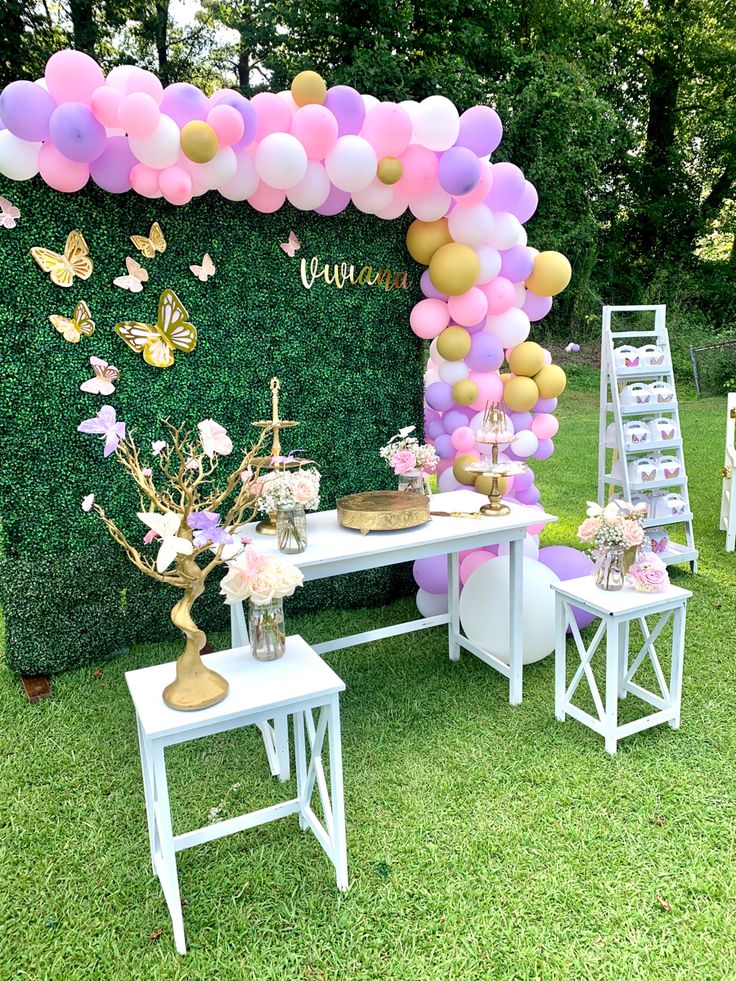 a table topped with balloons and flowers on top of a lush green grass covered field