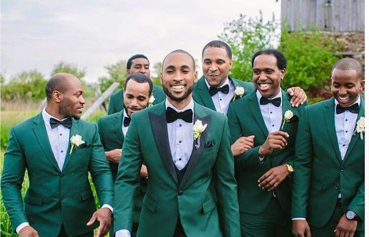 a group of men in green tuxedos posing for a photo with each other