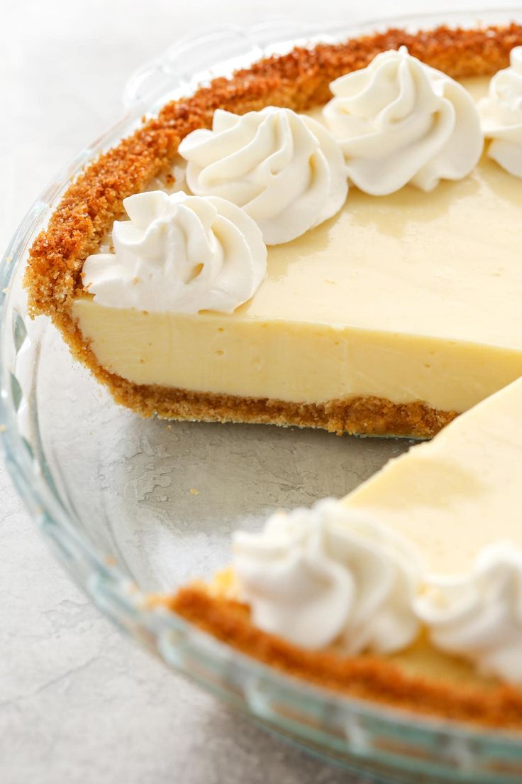 a cheesecake with whipped cream on top in a glass pie plate, ready to be eaten