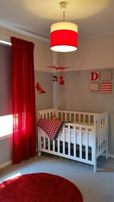 a baby's room is decorated in red and gray colors with white crib