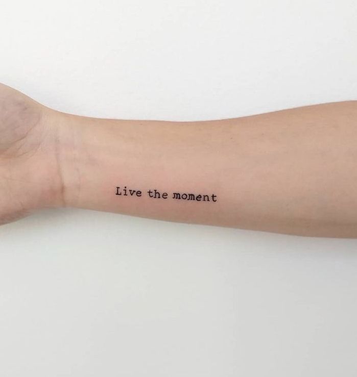 a person's arm with the words live the moment tattooed on it, in black ink