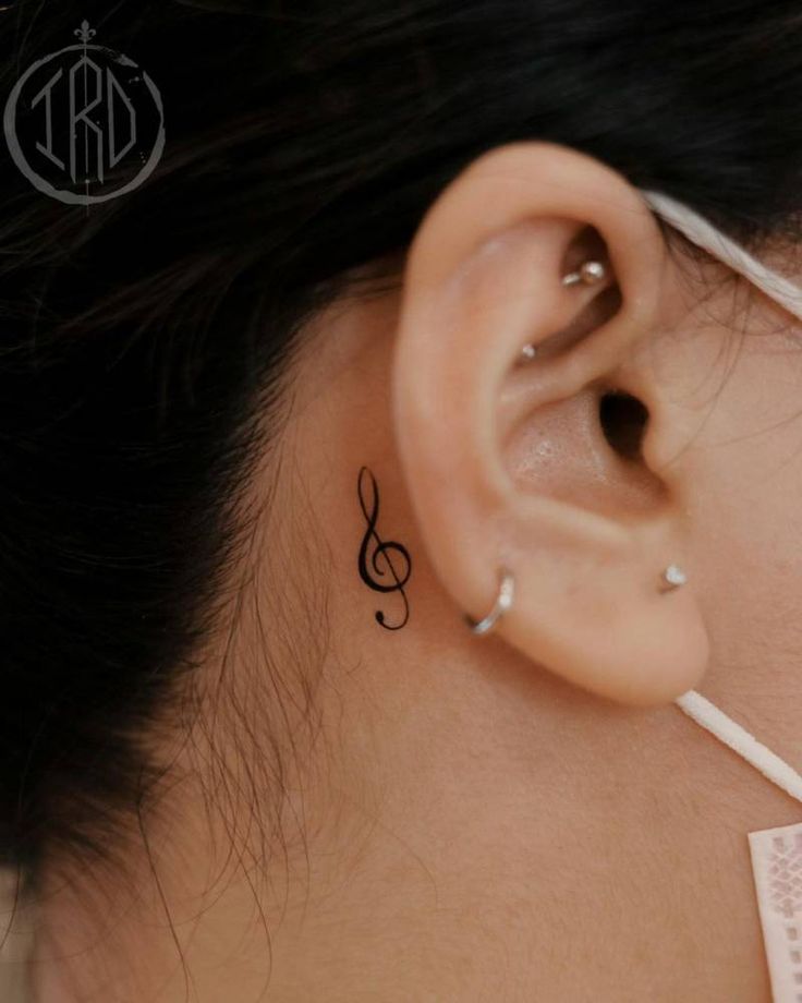 a close up of a person's ear with a musical note tattoo on it