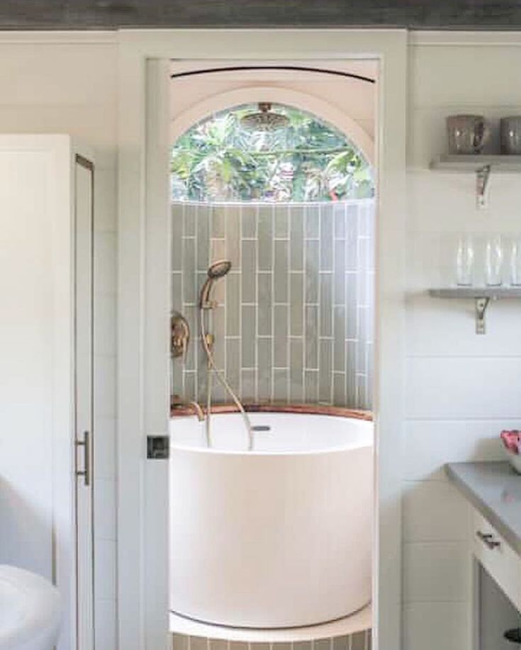 a bathroom with a bathtub and sink inside of it, next to a window