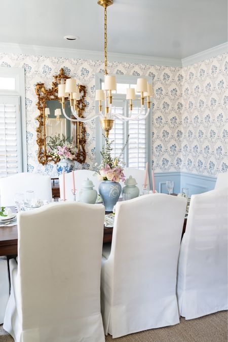 a dining room table with white chairs and a mirror on the wall above it,