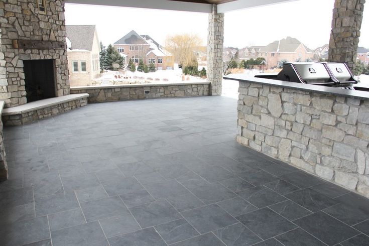 an outdoor patio with stone fireplace and seating area