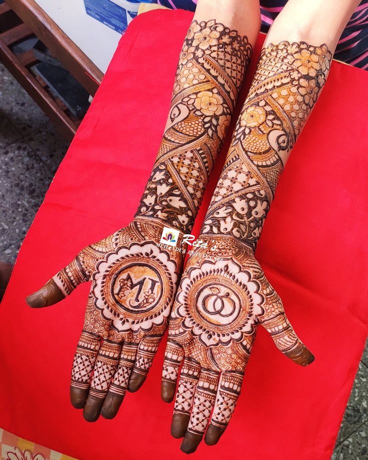 two hands with henna designs on them sitting next to each other in front of a red couch