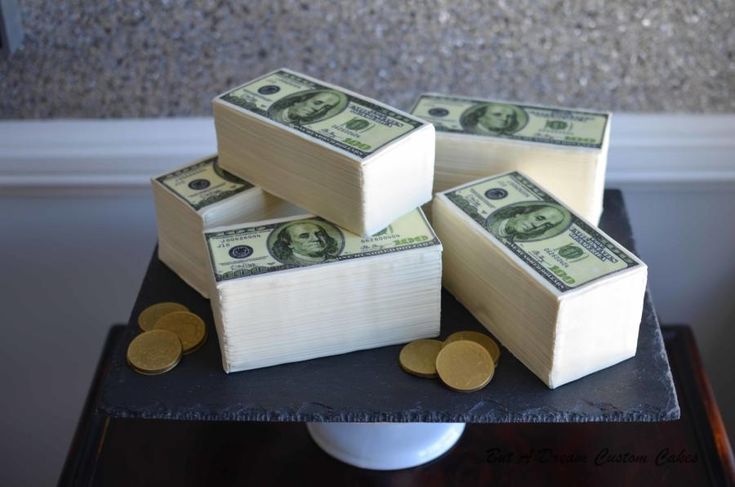 four stacks of money sitting on top of a black table next to some gold coins