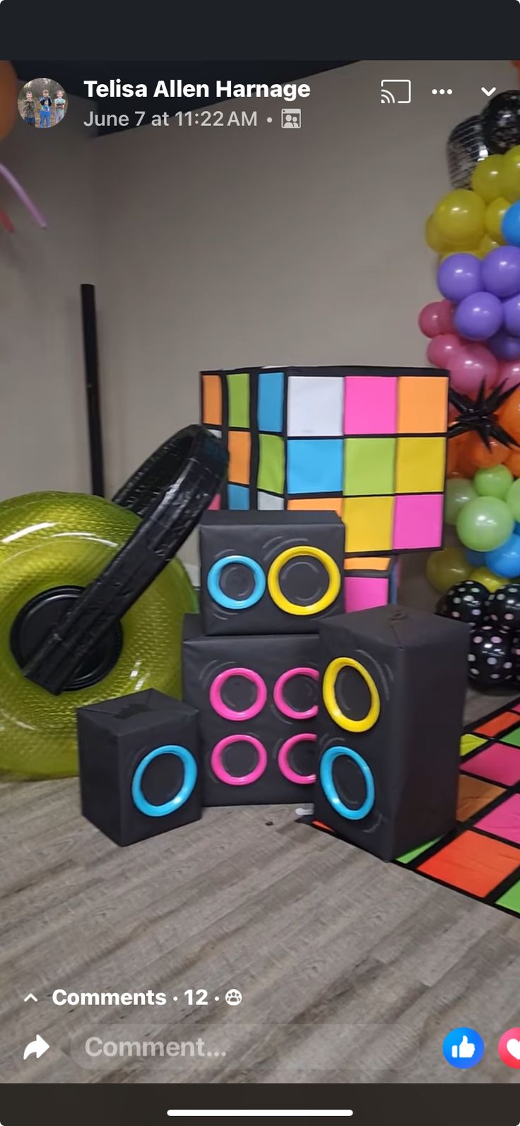 a table topped with lots of different colored rubik blocks and balloons in the background