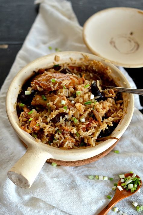 a bowl filled with rice and vegetables on top of a white cloth next to a wooden spoon