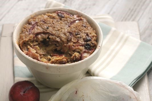 a bowl of food sitting on top of a table next to an apple and spoon