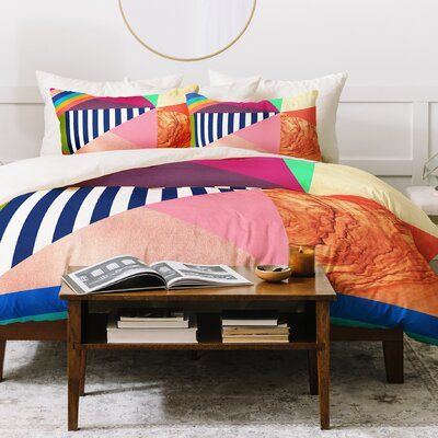 a bed with colorful comforters and pillows on it