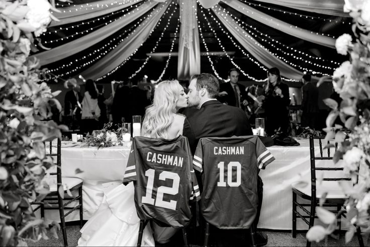 a bride and groom kissing in front of a decorated tent at their wedding breakfast table