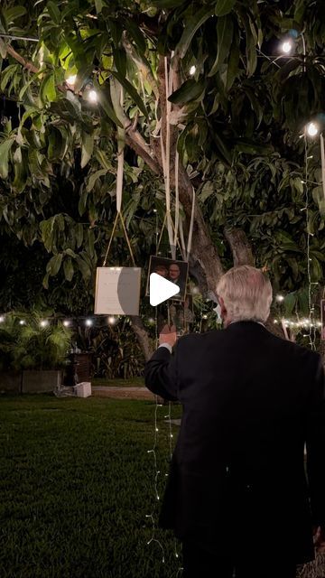 a man standing under a tree with lights on it