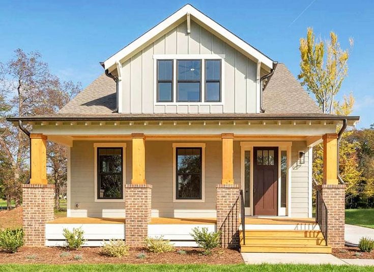 a small house with two front porches and steps leading to the front door, on a sunny day