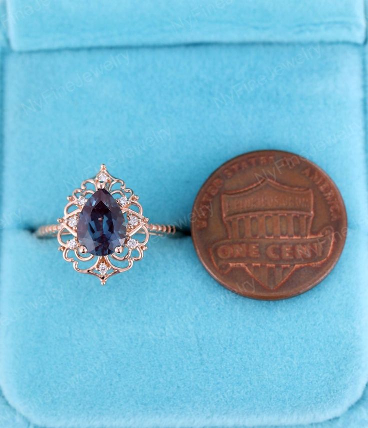 a ring with a blue stone sits next to a penny