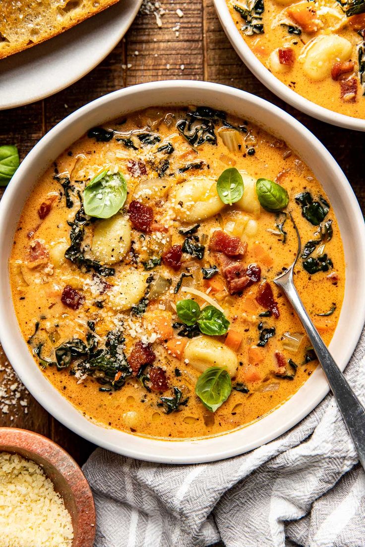 three bowls of soup with spinach, cheese and other toppings on the side