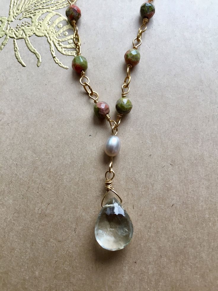 "A handmade chain of 12 faceted Unakite beads leads to a sparkling, faceted Green Amethyst drop hanging by a small Fresh Water Pearl. The closure features an additional Unakite bead. - 18\" long - gold-fill chain - Unakite, Pearl, and Green Amethyst - strong gold-fill clasp Arrives in a beautifully wrapped box with a gold-embossed bee design on the cover, a ribbon, and matching tissue paper." Artisan Jewelry With Faceted Beads As A Gift, Artisan Jewelry With Faceted Beads For Gifts, Teardrop Gemstone Beads Jewelry Gift, Teardrop Gemstone Beads For Gifts, Spiritual Teardrop Beaded Necklaces For Jewelry Making, Teardrop Natural Stones Gemstone For Gift, Briolette Gemstone Bead Necklace As A Gift, Briolette Gemstone Beads Necklace As Gift, Artisan Necklace With Faceted Beads For Gifts