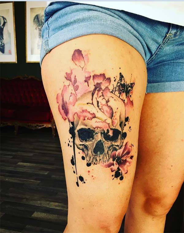 a woman's thigh with a skull and flowers on it