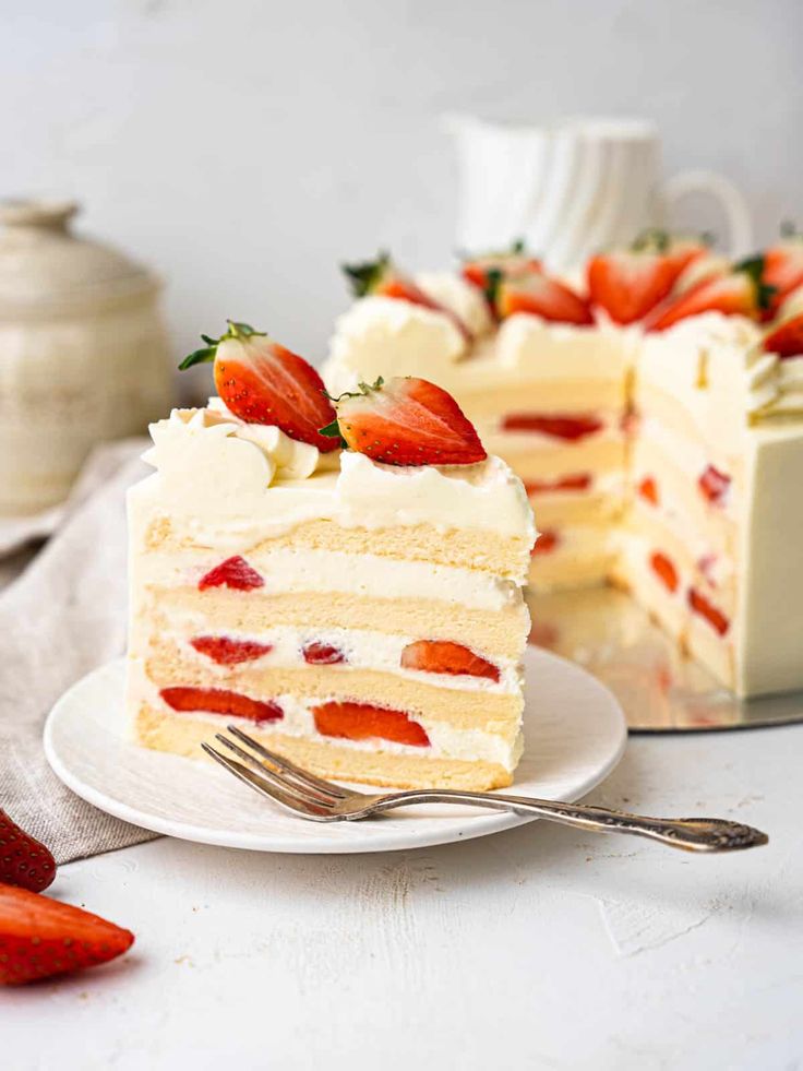 a slice of strawberry layer cake on a white plate with a fork next to it