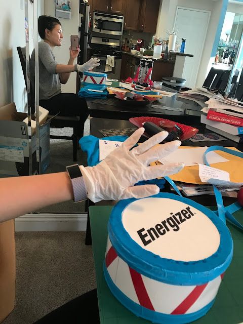 a woman in white gloves is standing near a table with boxes and other items on it