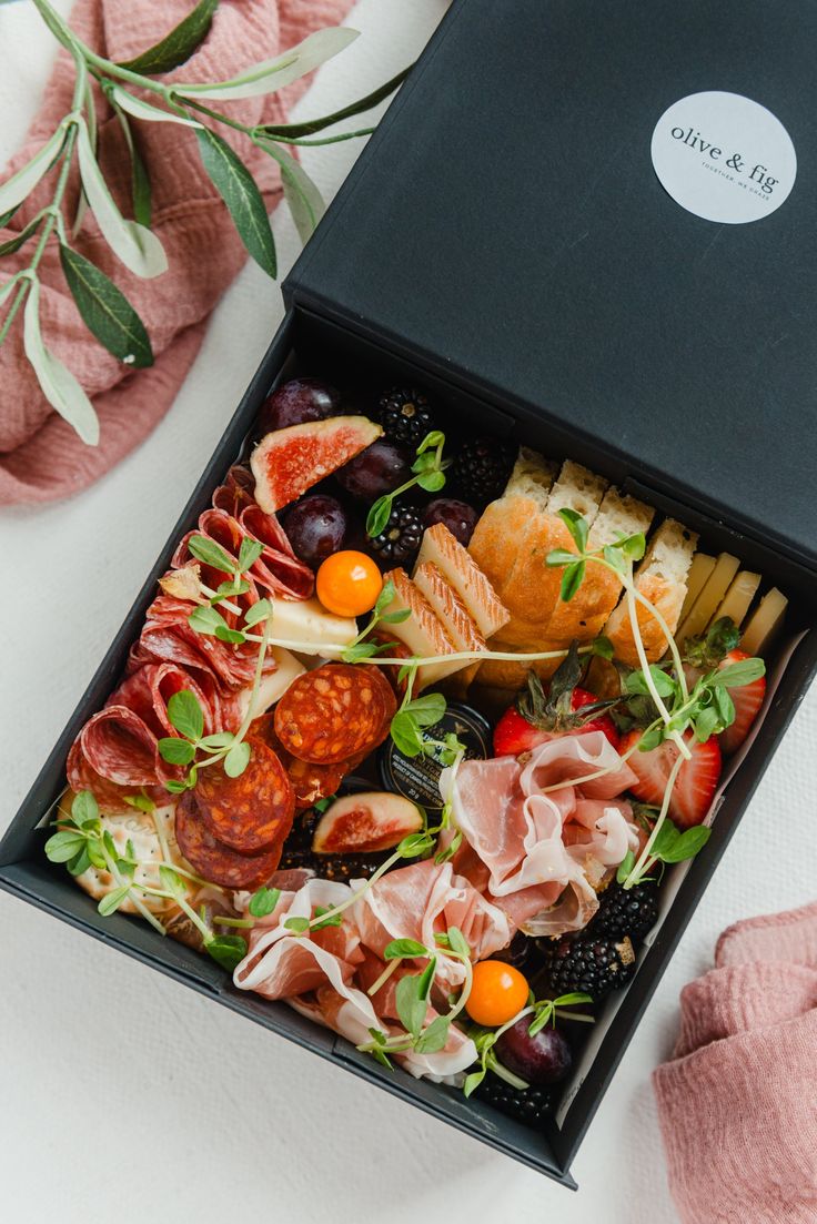 a black box filled with assorted meats and veggies on top of a white table