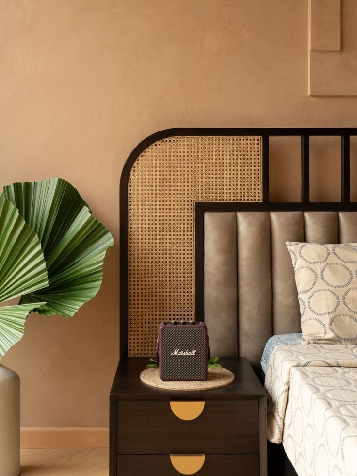 a bed sitting next to a vase with a plant in it on top of a table